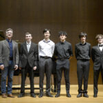 people standing on stage in front of piano