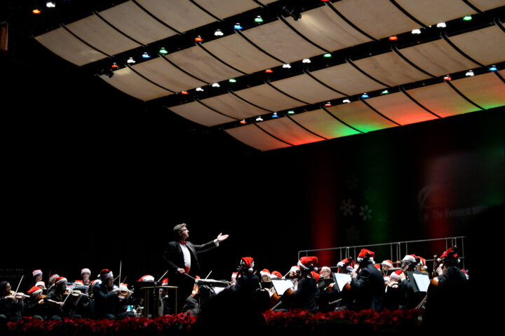 orchestra on stage wearing santa hats