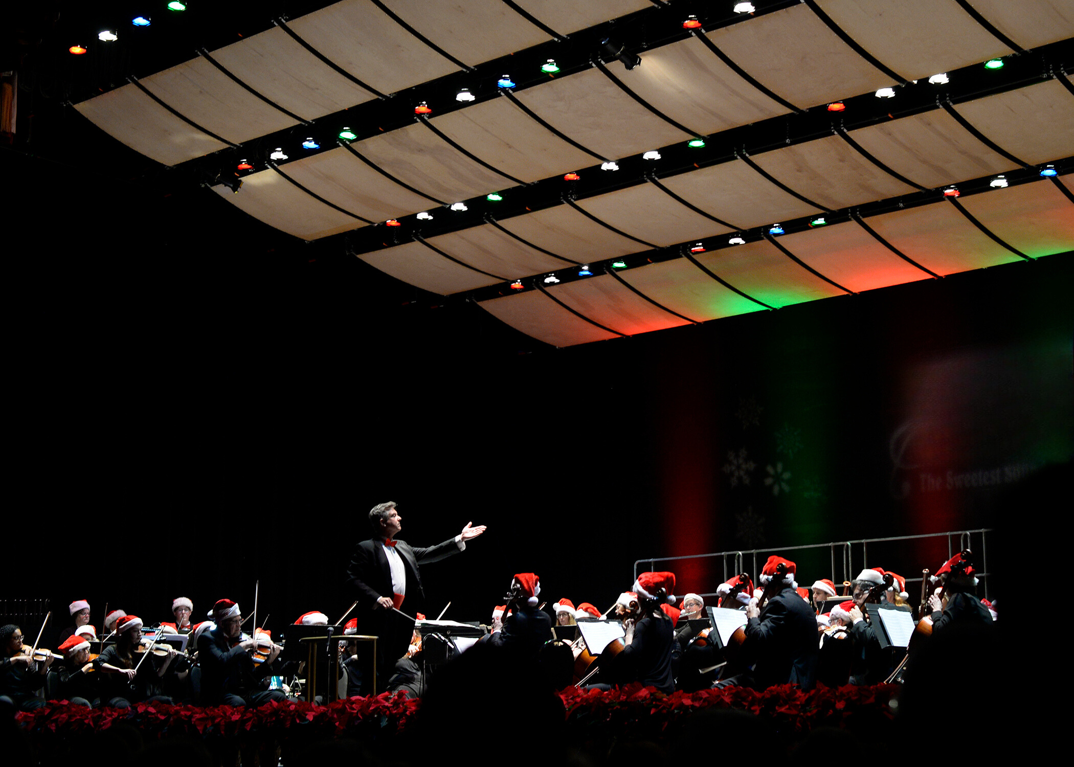 orchestra on stage wearing santa hats