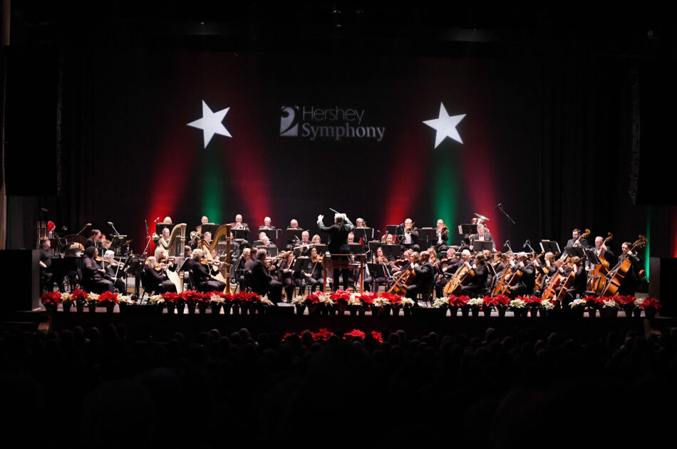 symphony orchestra on stage with holiday decorations