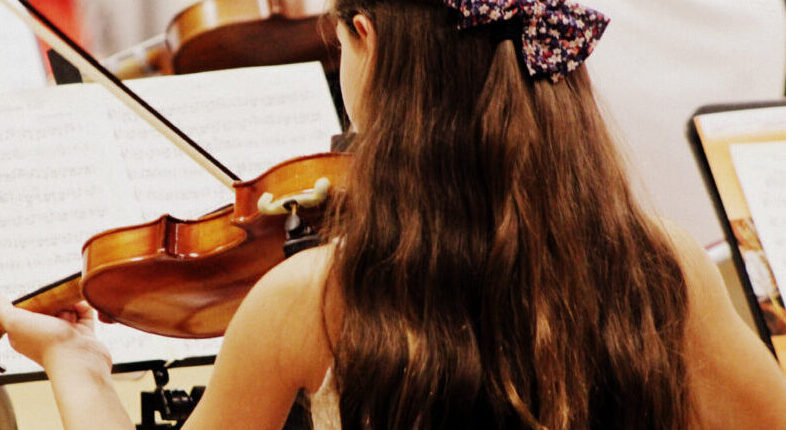 girl playing violin seen from behind