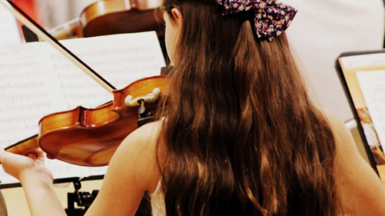 Young girl playing the violin seen from behind. Hershey Festival Strings musician.