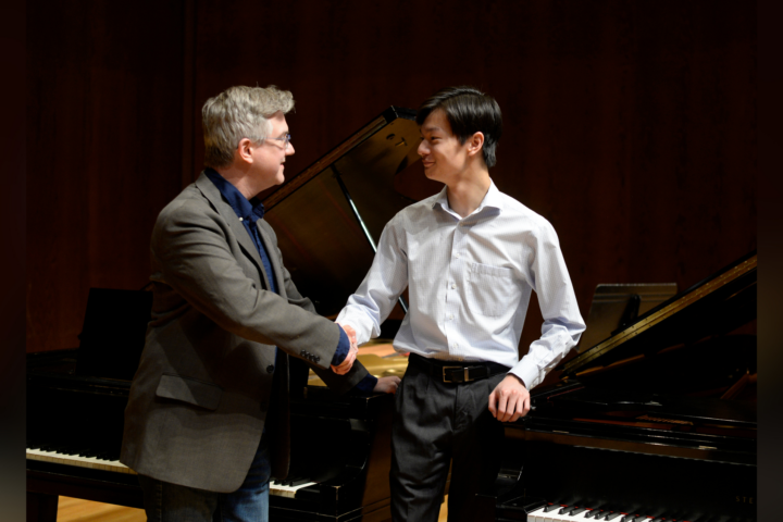 man and teenage boy shaking hands in front of piano